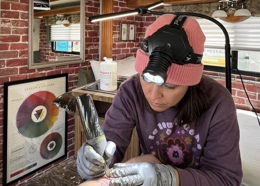 Tatoueuse au travail dans un studio de tatouage mobile aménagé dans un VR